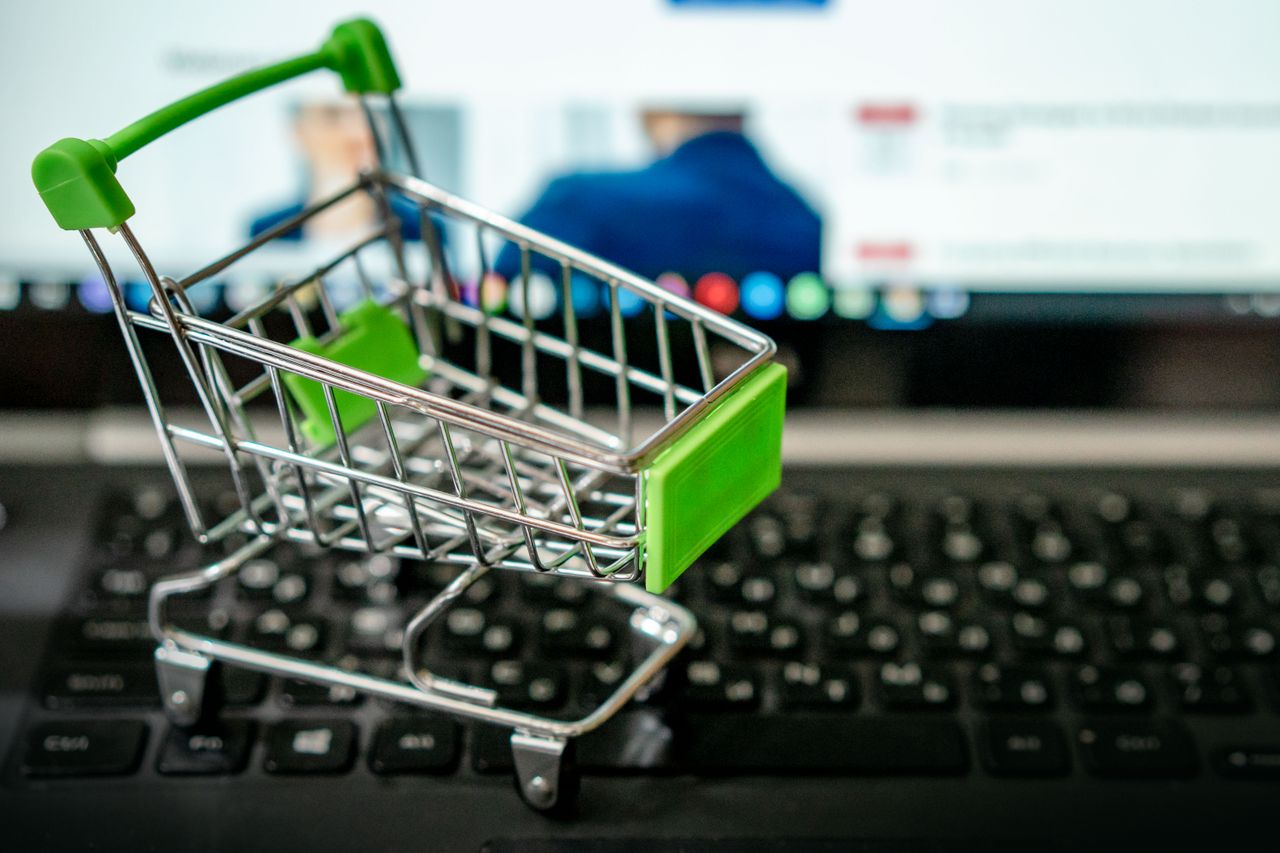 about-us-02 Miniature shopping cart placed on a laptop keyboard, symbolizing online shopping.
